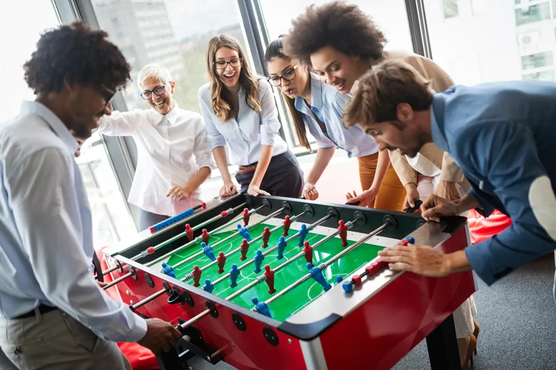 group at work playing table soccer, they could be playing during a year end party