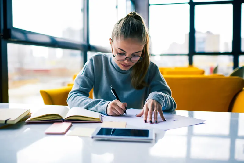 a young lady working using corporate gifts such as branded pen and notebooks